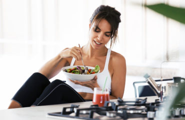 Fit Woman Eating Salad After Pur-Pharma Gym Workout with Smoothie