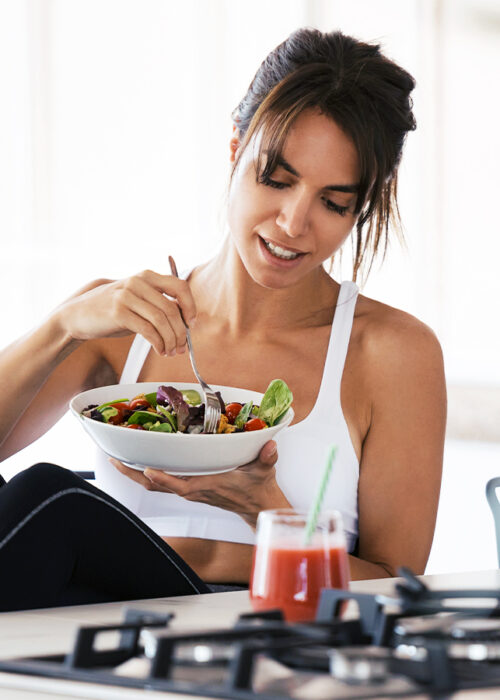 Fit Woman Eating Salad After Pur-Pharma Gym Workout with Smoothie