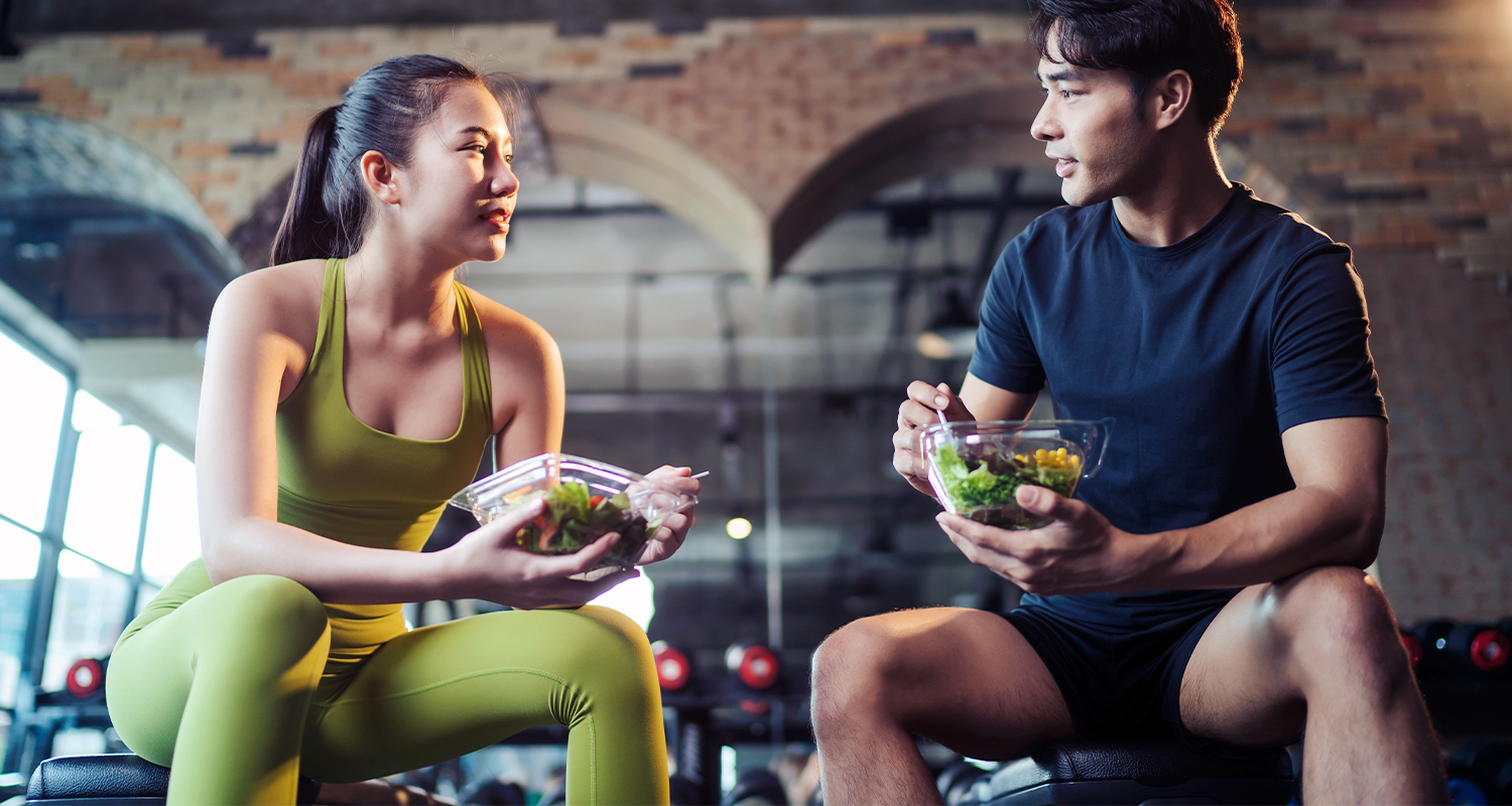 Asian Man and Woman Eating Salads at Modern Pur-Pharma Gym
