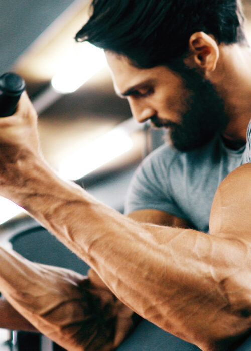 Fit Lean Man Exercising Bicep Curls in Gym