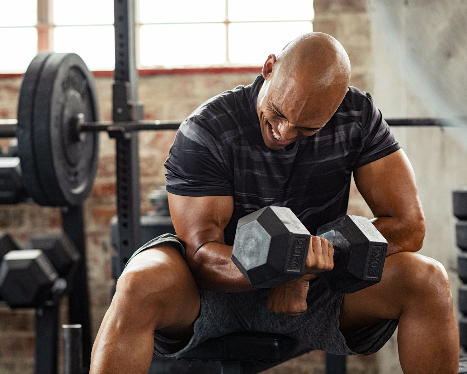 Fit African American Man Doing Concentration Bicep Curl with Dumbbell on Bench