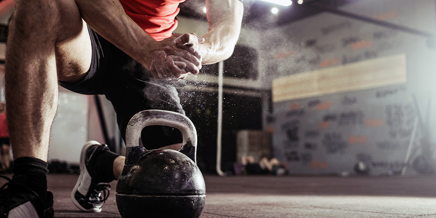 Athletic Man Lifting Kettlebell with Chalk