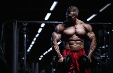 Muscular guy in red shorts holding dumbells