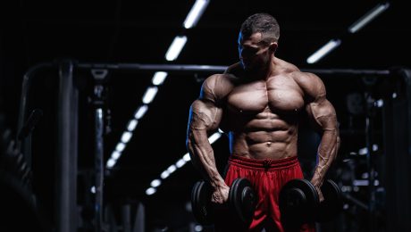 Muscular guy in red shorts holding dumbells